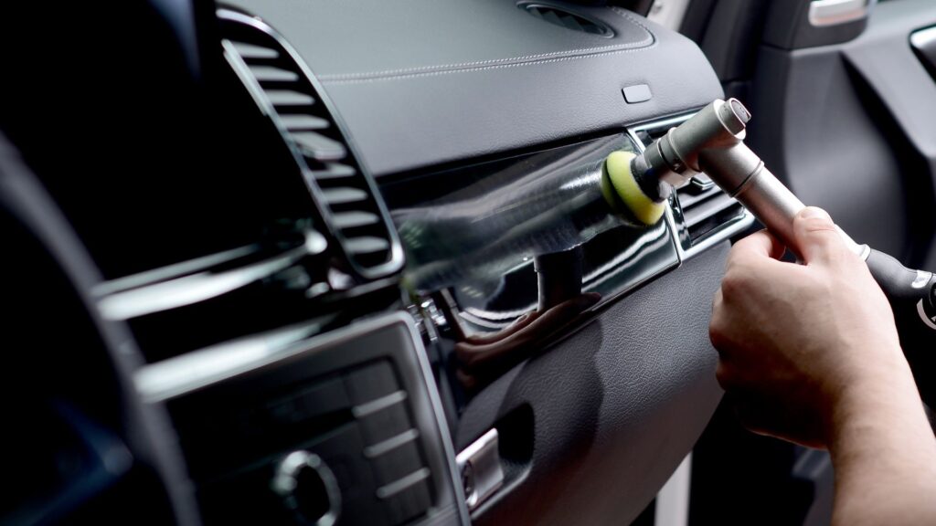 A worker uses a special tool to clean the interior of a car